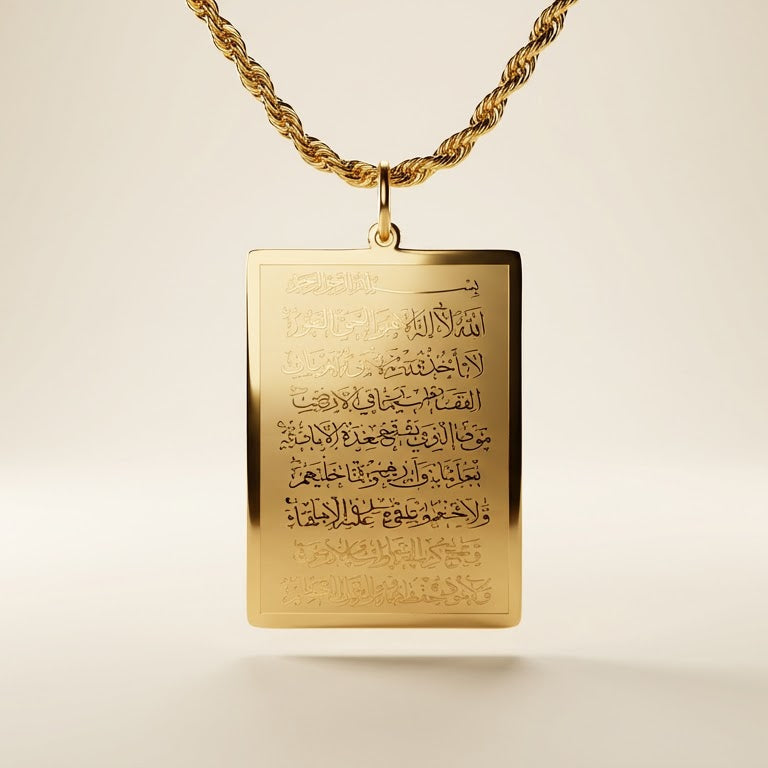Gold pendant with engraved ayatul kursi on a light background