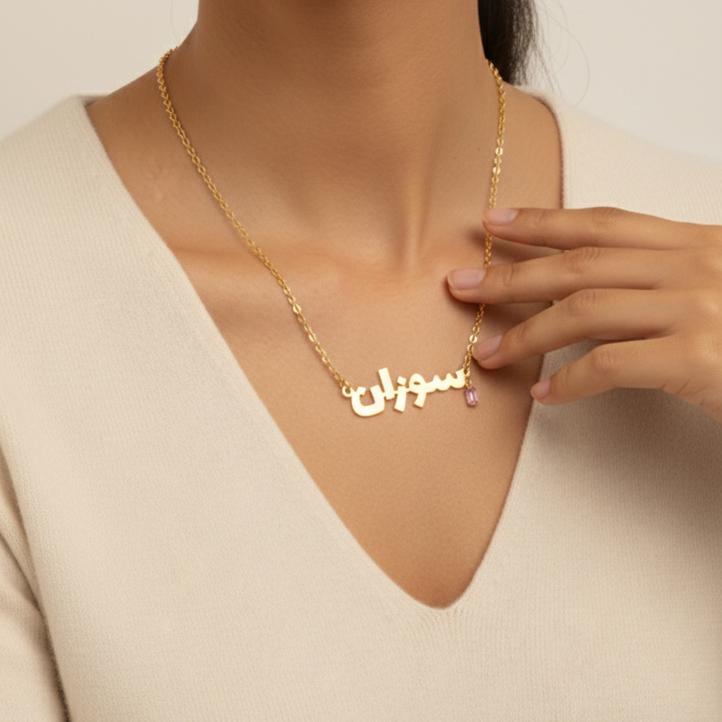 Woman wearing a gold name necklace with a beige background