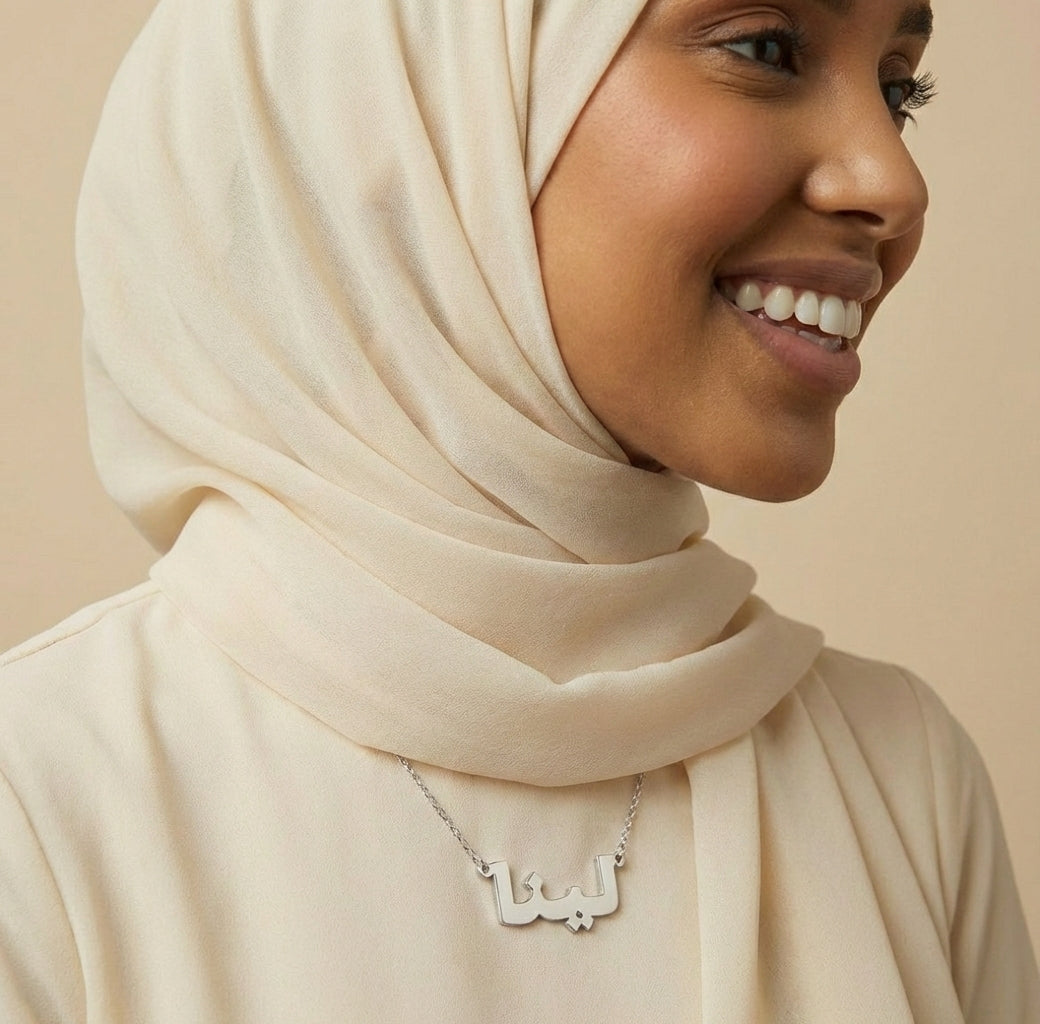 Woman wearing a beige hijab and a necklace with a pendant on a beige background
