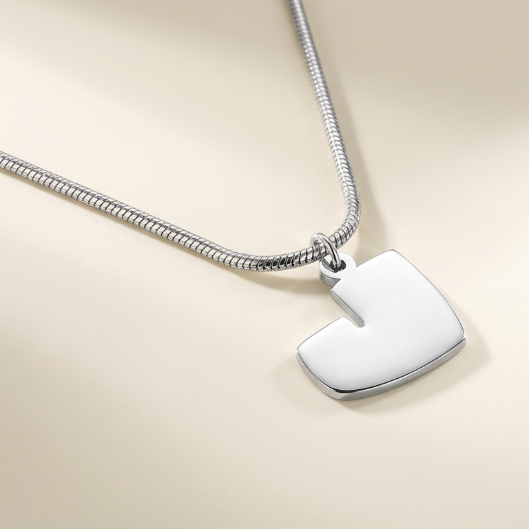 Silver necklace with a arabic shaped pendant on a beige background