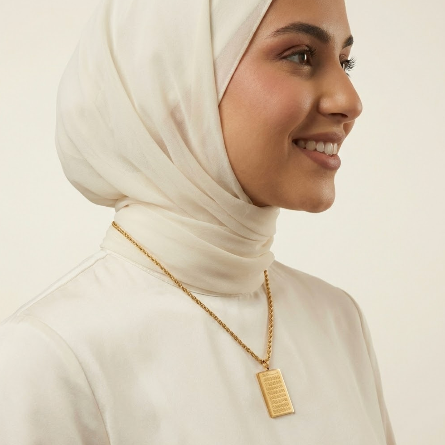 Woman wearing a gold ayatul kursi necklace with a pendant on a plain background