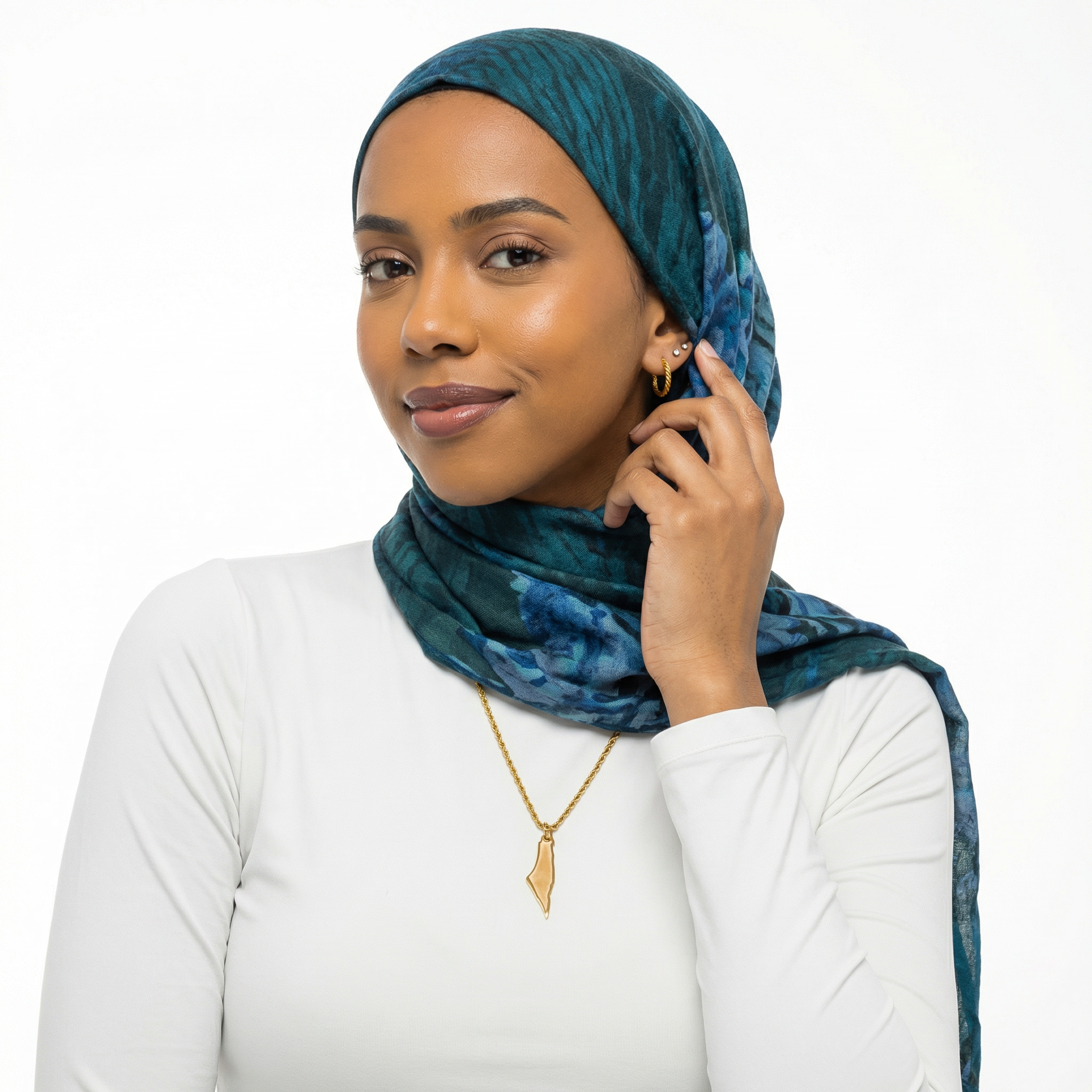 Woman wearing a teal hijab and white top on a white background