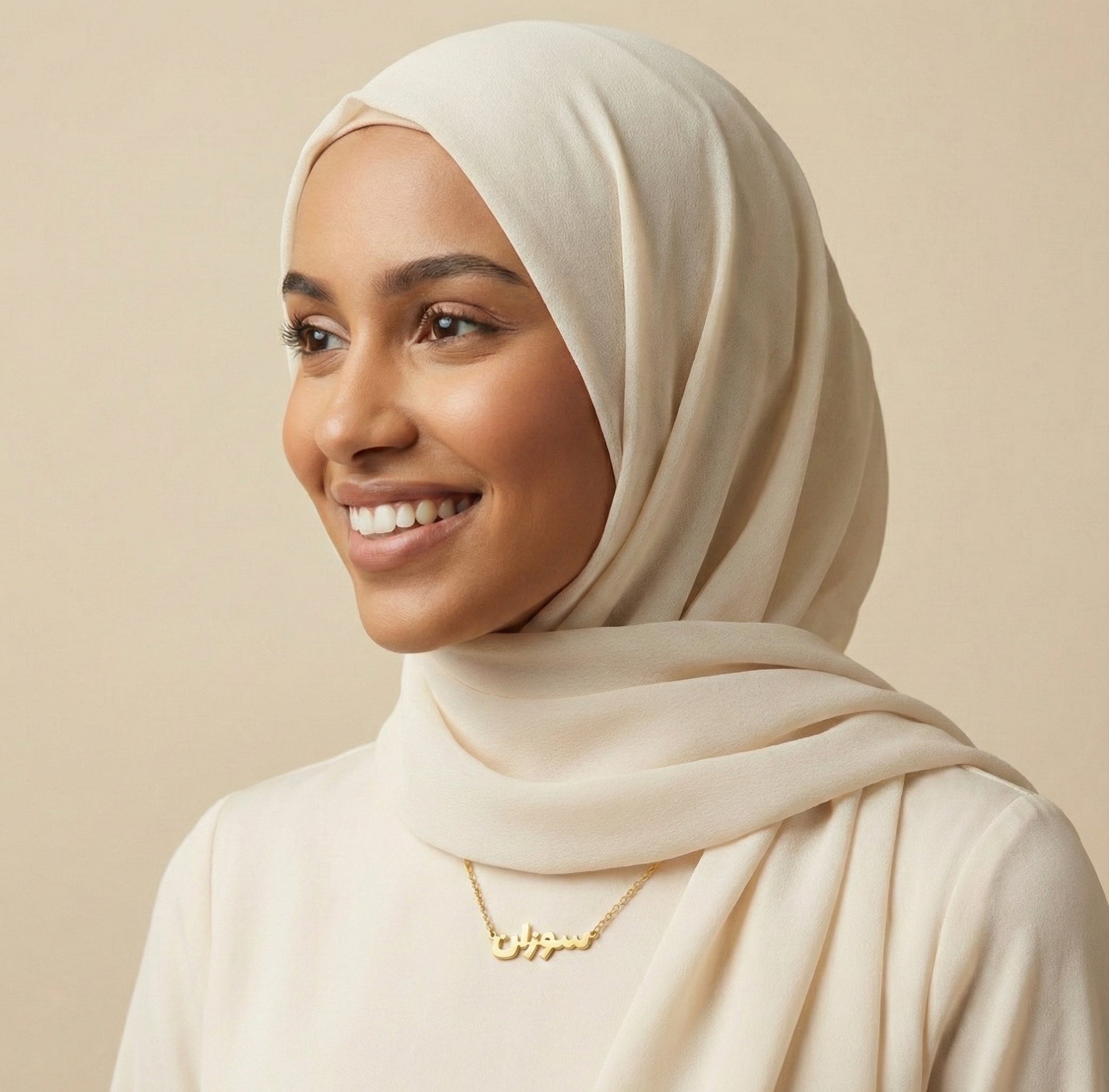 Woman wearing a beige hijab and white top against a beige background