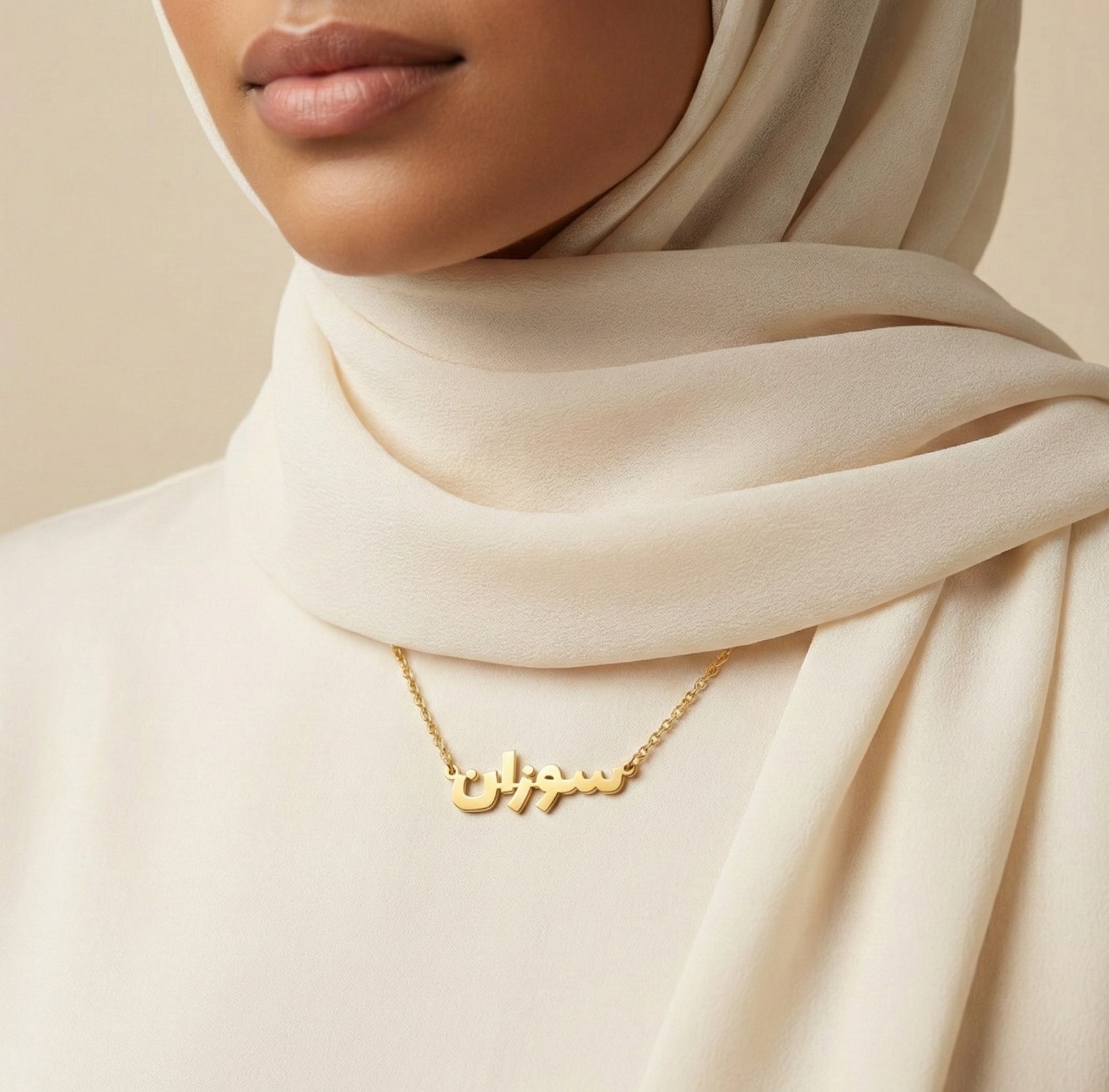 Woman wearing a gold necklace with Arabic script against a beige background