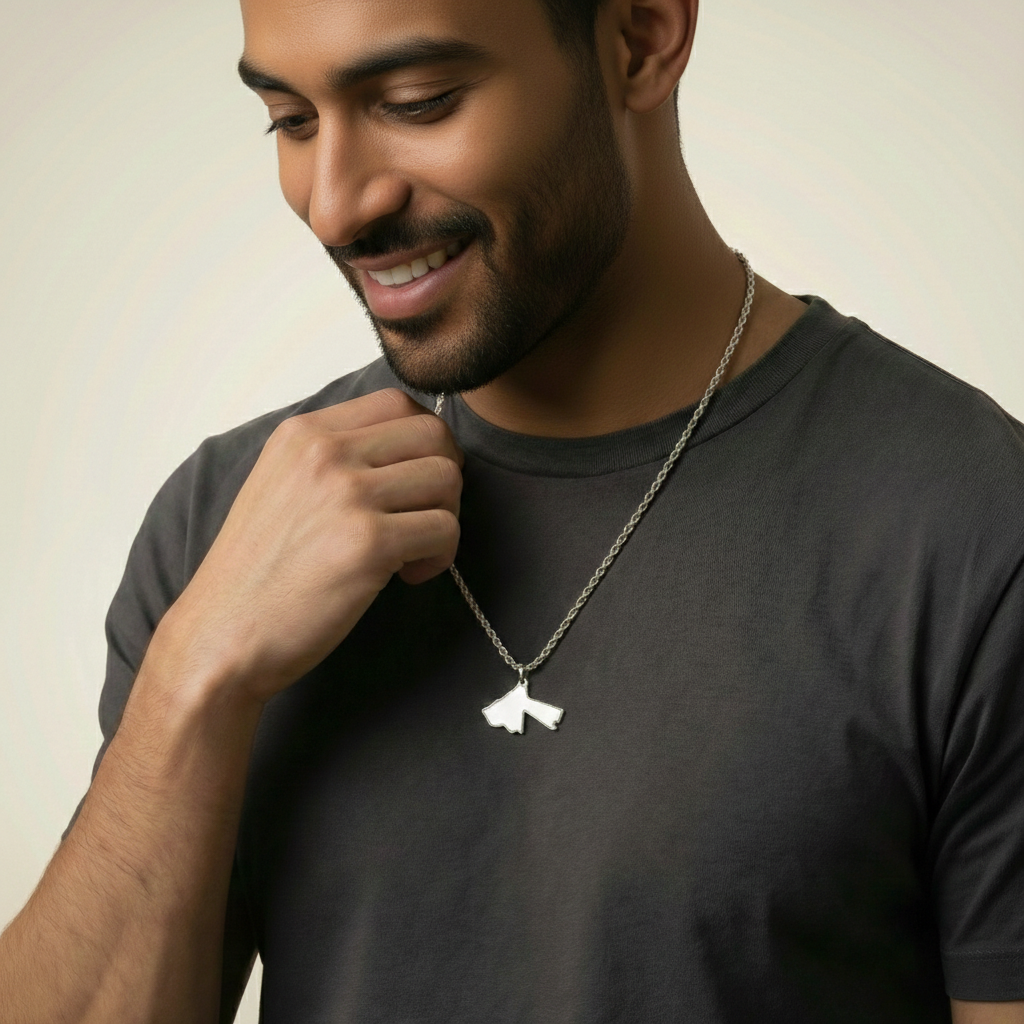 Man wearing a dark gray t-shirt and a necklace with a bird pendant against a neutral background