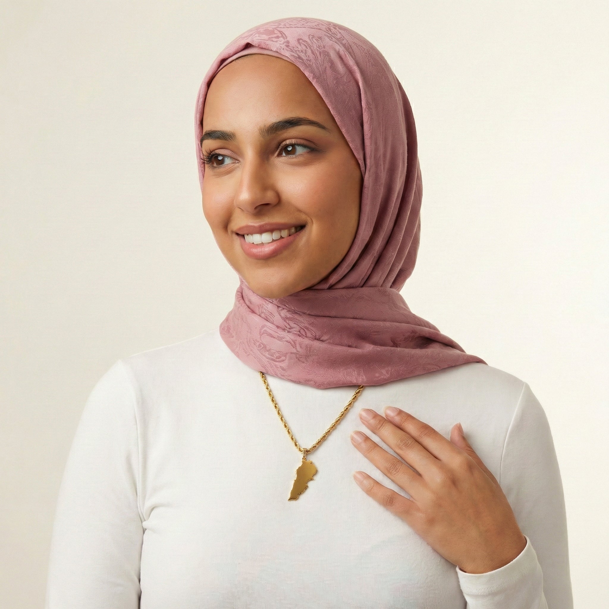 Woman wearing a pink hijab and white shirt with a neutral background