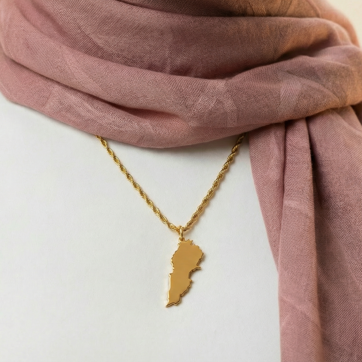 Gold necklace with a pendant lebanon wearing a pink scarf.