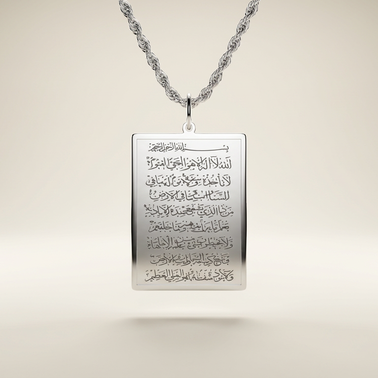 Silver pendant with engraved ayatul kursi on a beige background