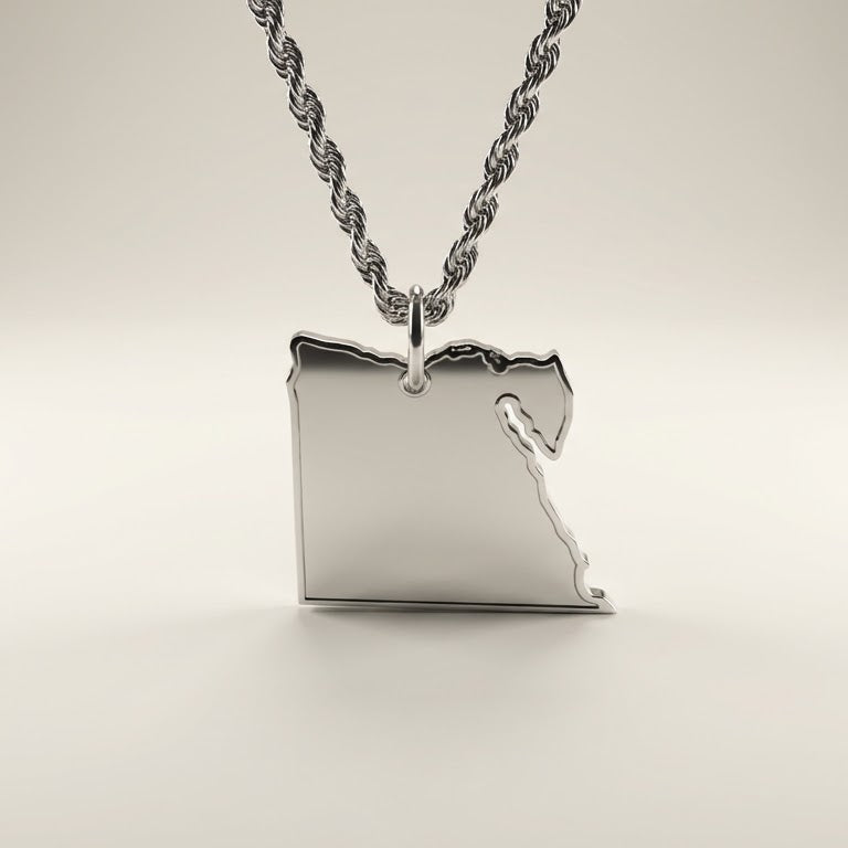 silver necklace with a pendant shaped like the country of egypt on a light beige background