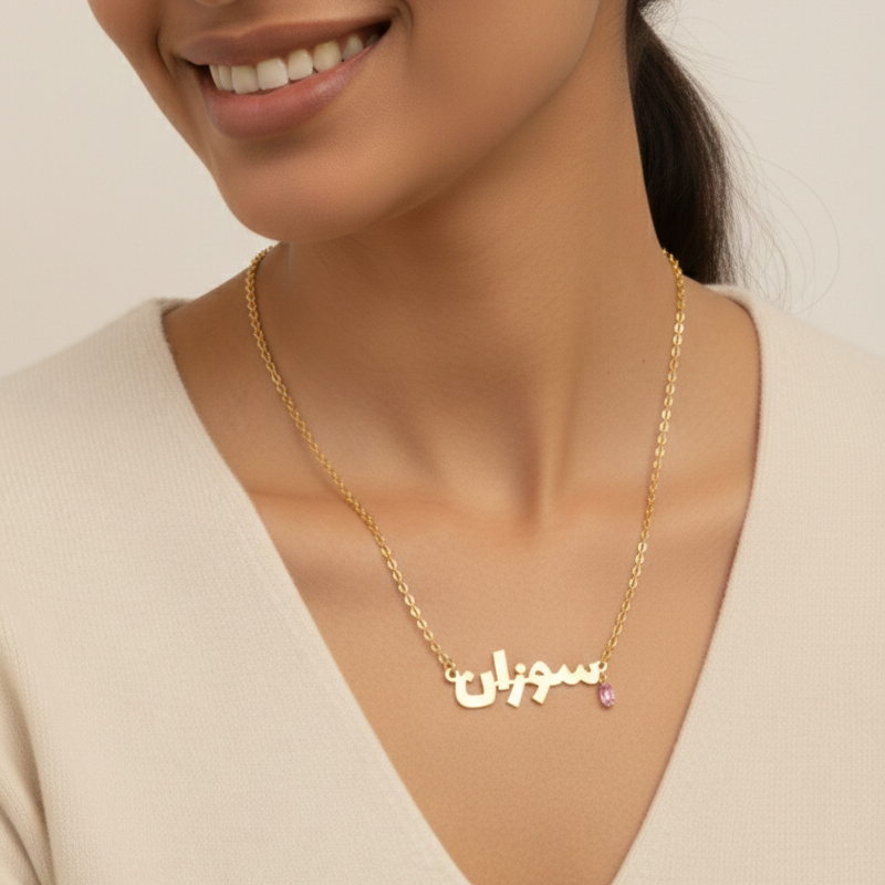 Woman wearing a gold necklace with Arabic script on a plain background